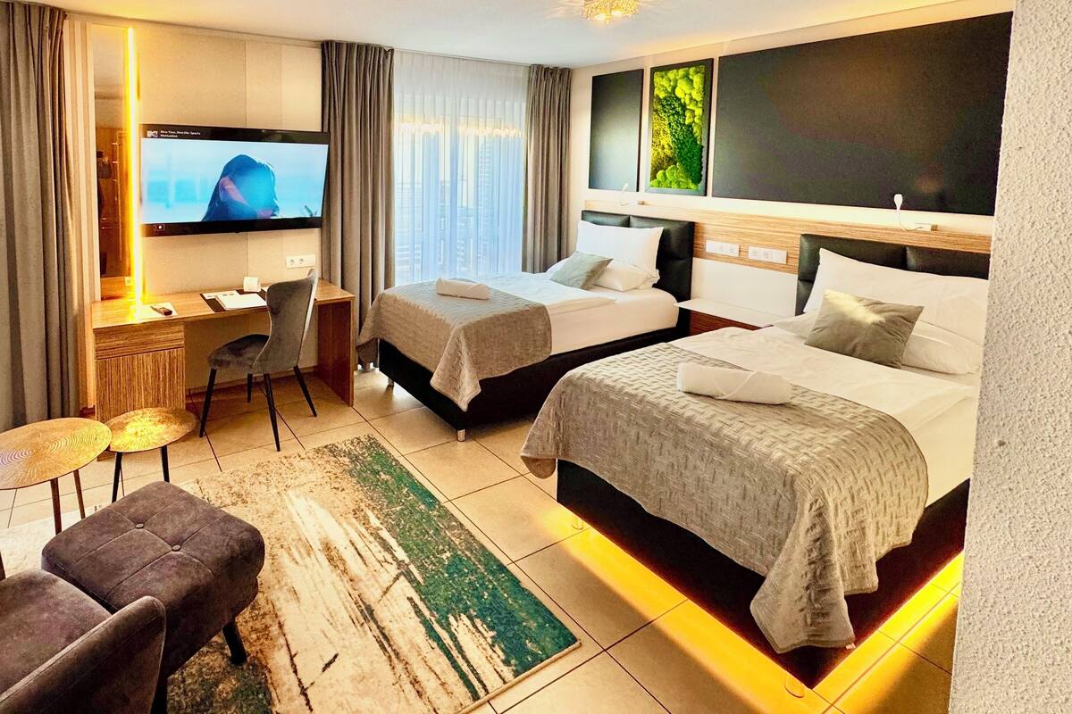 Ein Hotelzimmer mit Bett, Schreibtisch, Stuhl, Fernseher und Blick auf die Stadt.