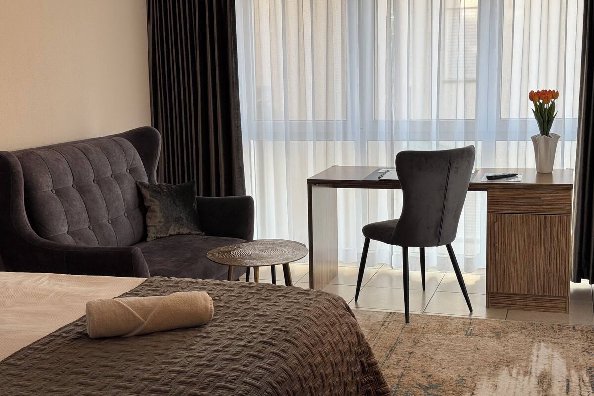 Ein modernes Hotelzimmer mit einem großen Bett, einer Couch, einem Schreibtisch und einem Sessel.