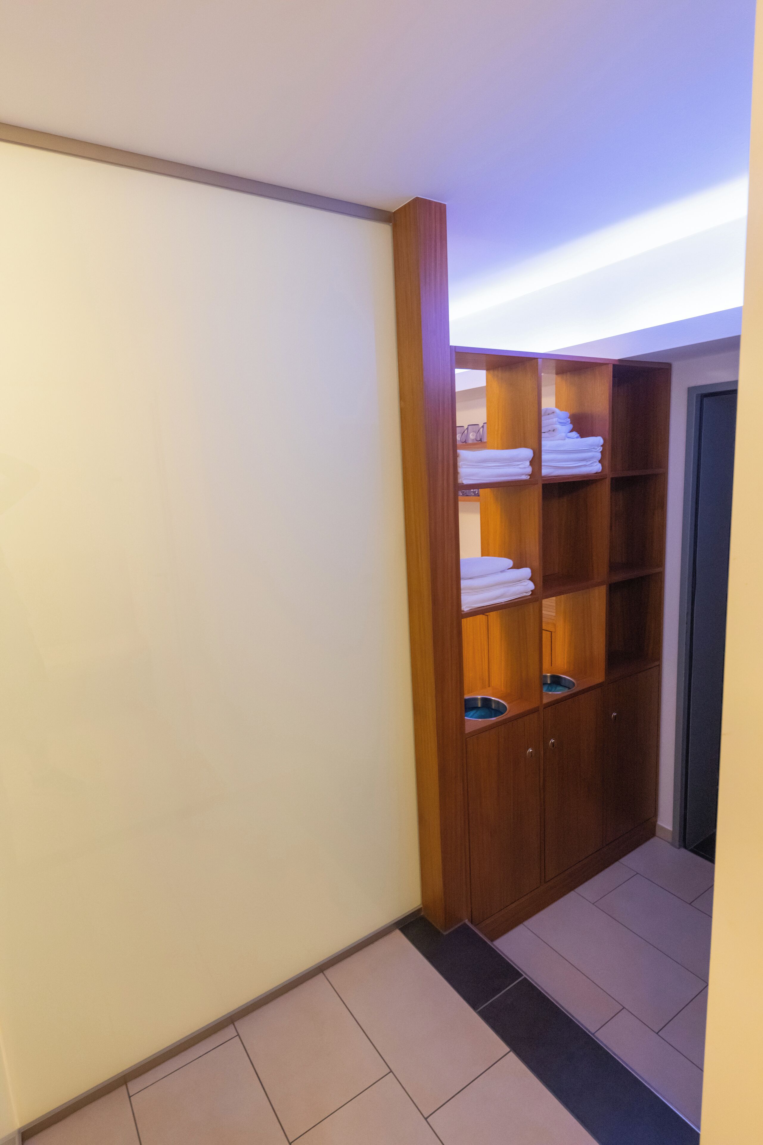 Ein Flur mit einem Holzschrank, der gefaltete Handtücher und eine Tür zu einem Zimmer enthält.