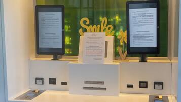A check-in counter with two monitors, a sign, and a reception desk.