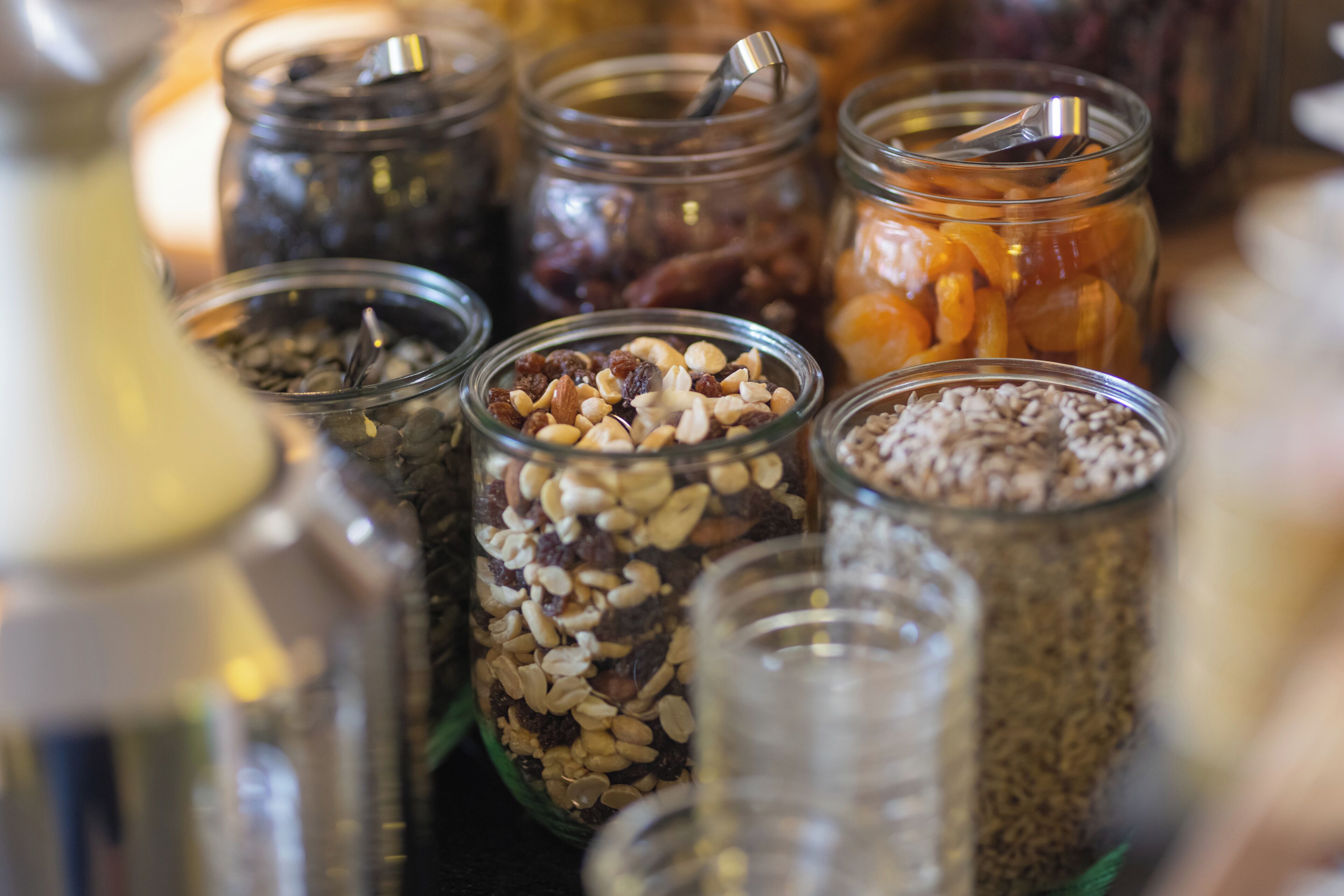 Multiple glass jars filled with various nuts and seeds.