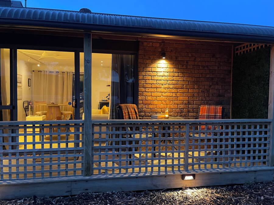 A cozy outdoor seating area with a table and chairs, a brick wall, and a glass door leading into a room.