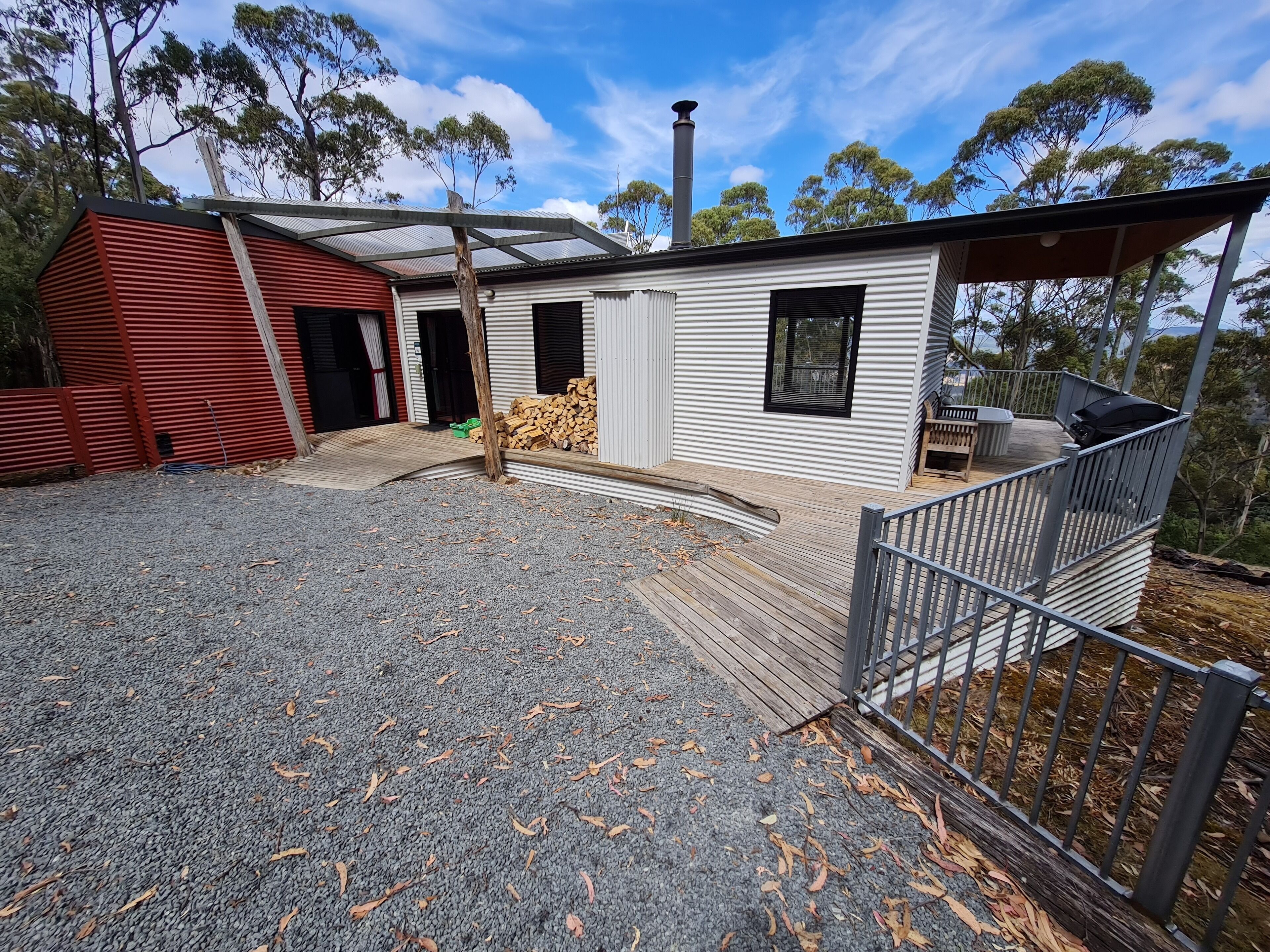 A modern house with a covered deck, a chimney, and a fenced yard.