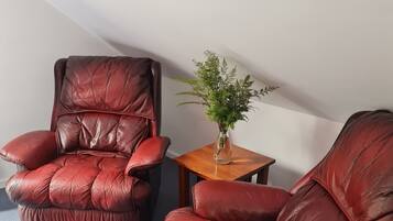 Two leather recliners in a room with a small wooden table and a potted plant.