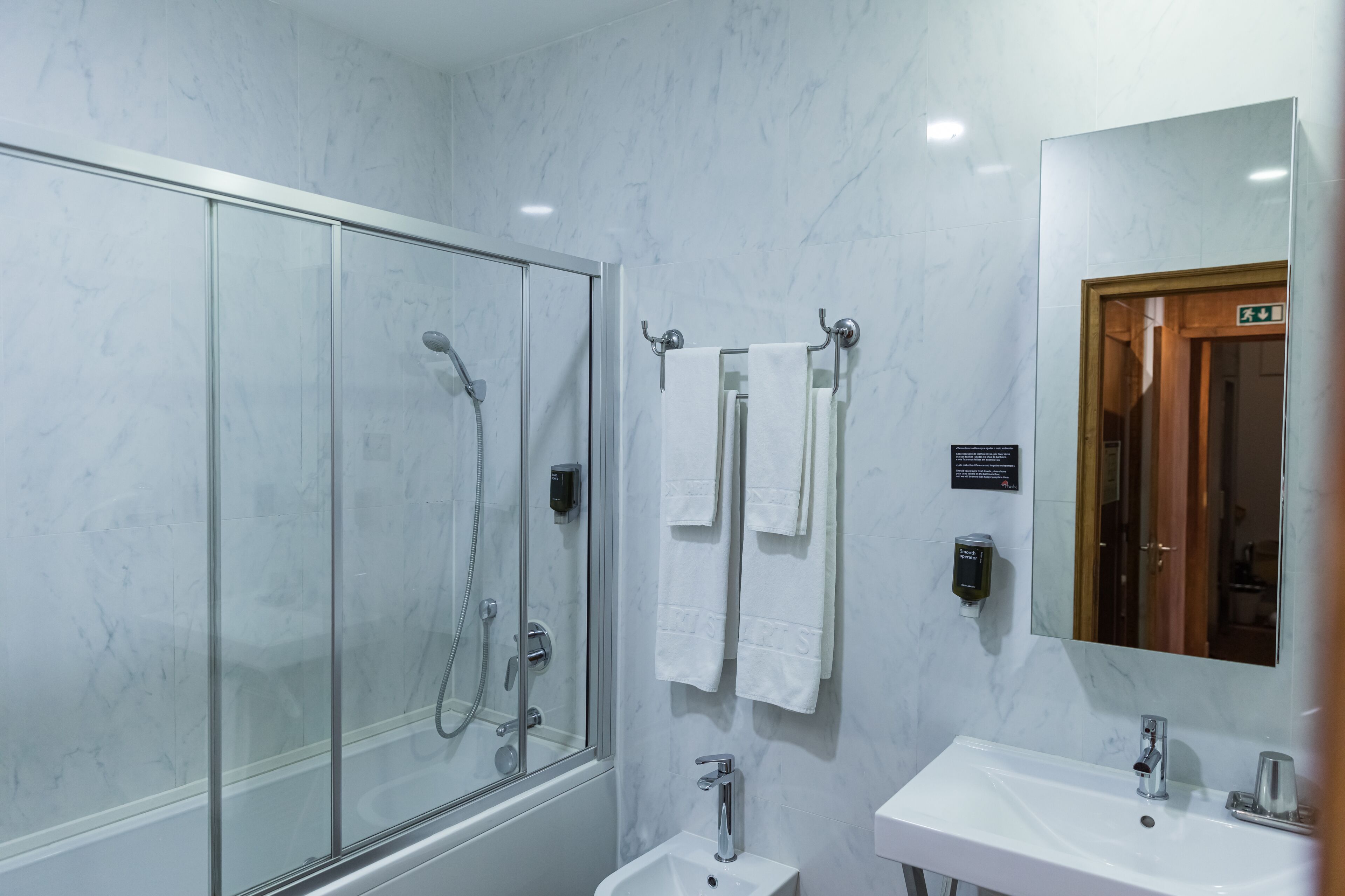 A modern bathroom with a glass-enclosed shower, a sink, and a mirror.