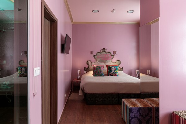 Un dormitorio con una cama grande, un televisor en la pared y un espejo que refleja la habitación.