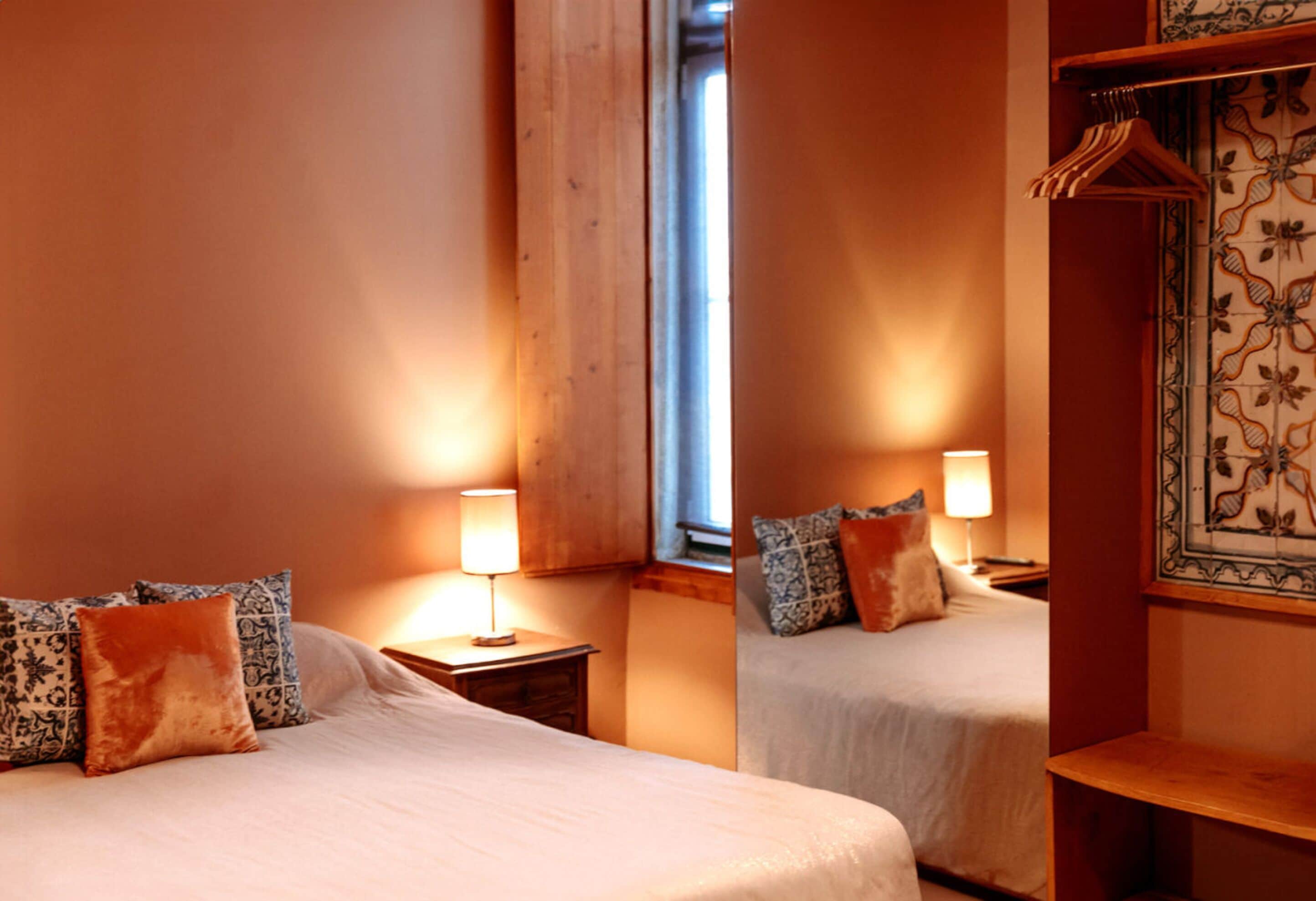 Une chambre d’hôtel avec deux lits, chacun doté d’une table de chevet et d’une lampe. On y trouve également une armoire en bois et un panneau décoratif mural.