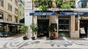 A Lisbon Art Stay building with a tiled pavement, potted plants, and outdoor seating.
