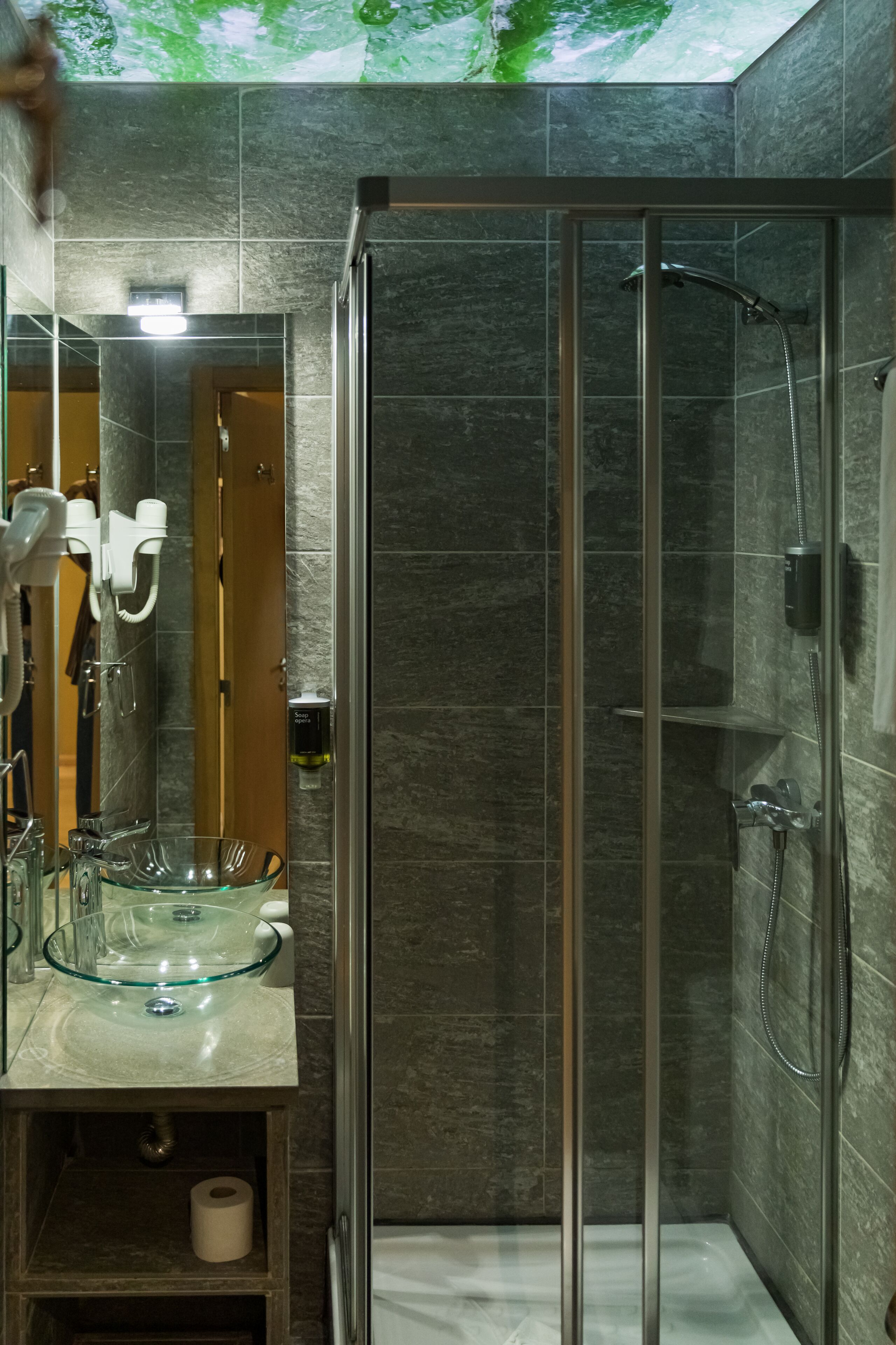 A modern bathroom with a glass shower enclosure, a glass sink, and a toilet.