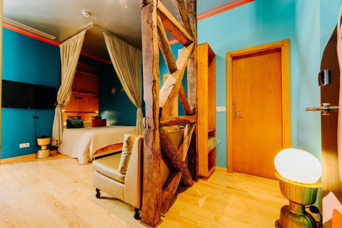 Una habitación con cama, una estructura de madera, una puerta y una lámpara de pie.