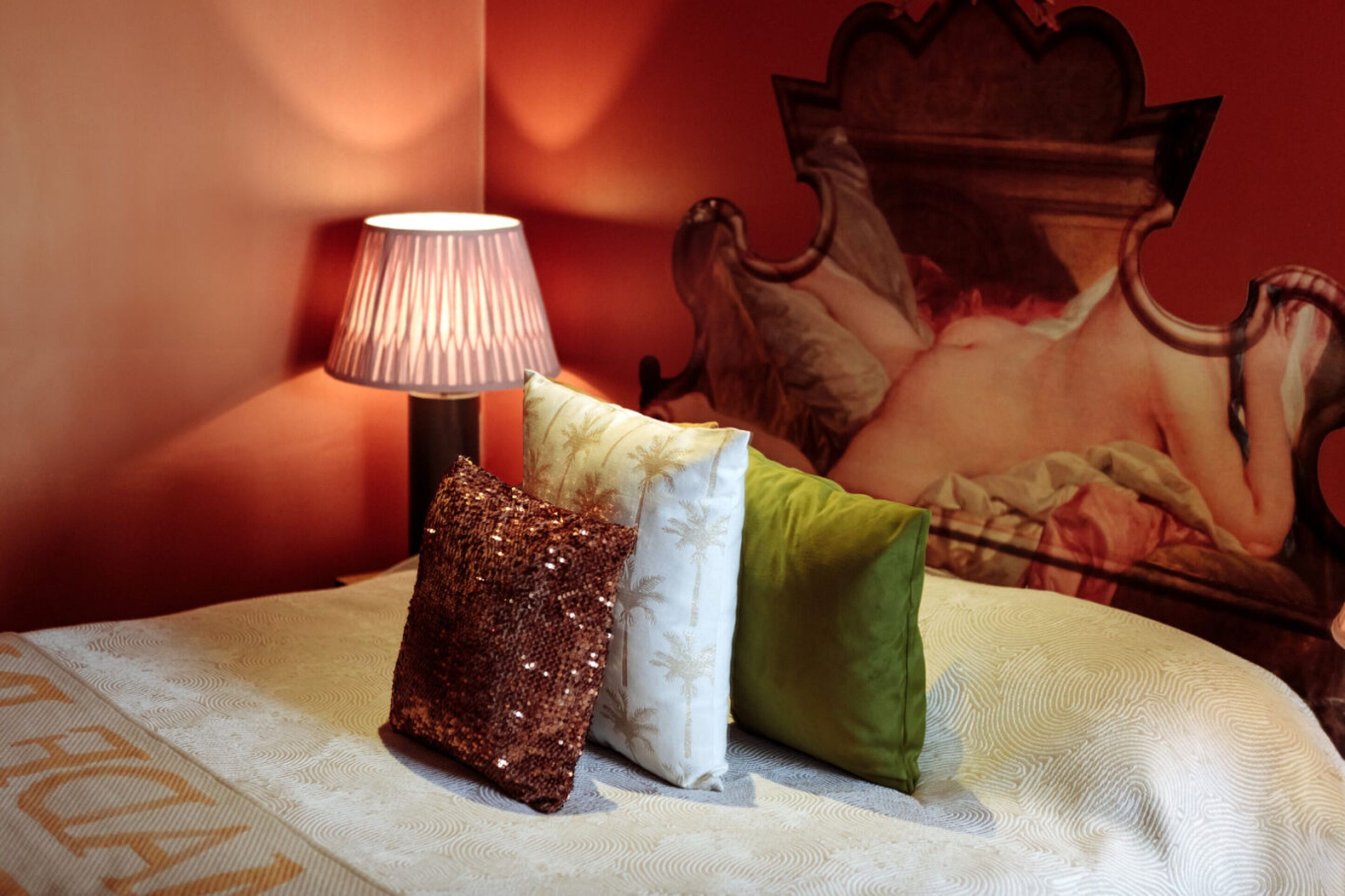 A bed with a decorative pillow, a lamp, and a painting on the wall.