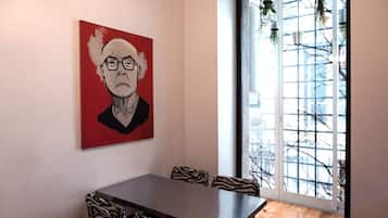 A dining area with a zebra-striped table and chairs, a red painting on the wall, and a view through a glass door.