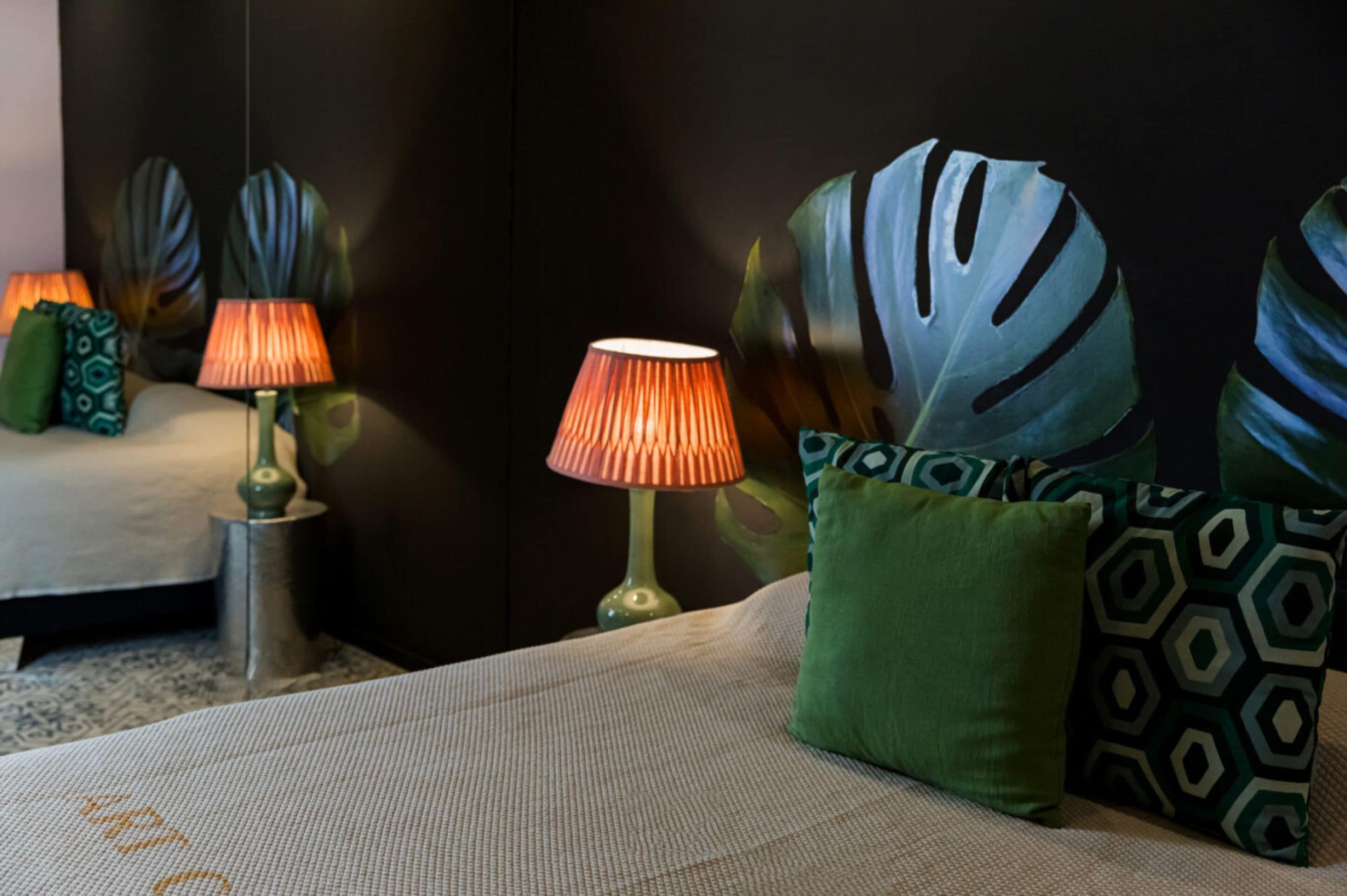 Een keurig opgemaakt hotelkamer met een bed, twee lampen en decoratieve kussens.