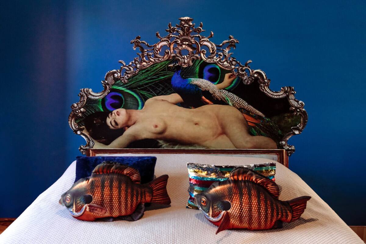 Una cama con un cabecero decorativo, dos almohadas y dos almohadas con forma de pez.