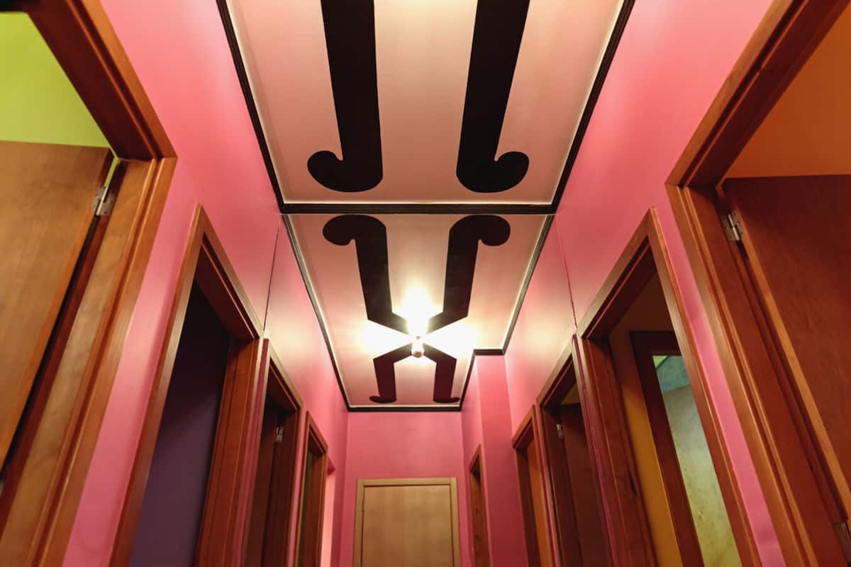 Un pasillo con paredes rosas y puertas de madera.