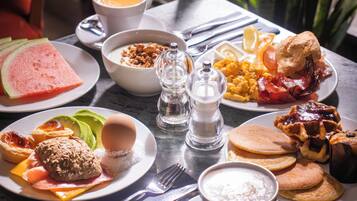 A breakfast table with various dishes including pancakes, eggs, bacon, and toast.