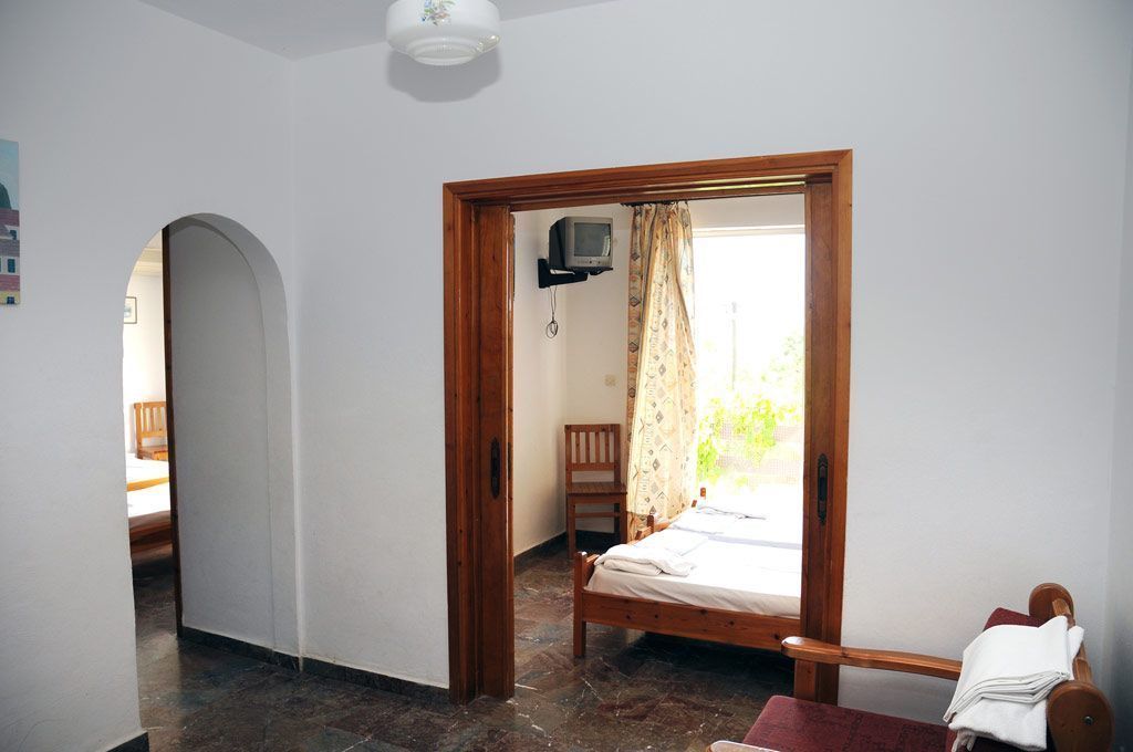 Ein Schlafzimmer mit einem hölzernen Bett, einem kleinen Fernseher und einem Sessel.