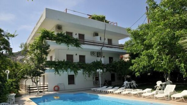 A two-story building with a swimming pool, white walls, and a flat roof. - Ninetta's Studios (Poros)