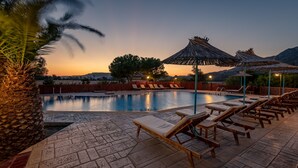 Une piscine entourée d’une terrasse dallée en pierre, agrémentée de chaises longues et de parasols.