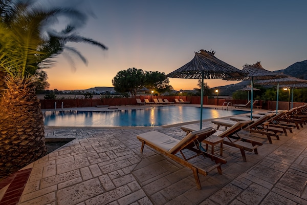 Una piscina al aire libre de temporada, sombrillas