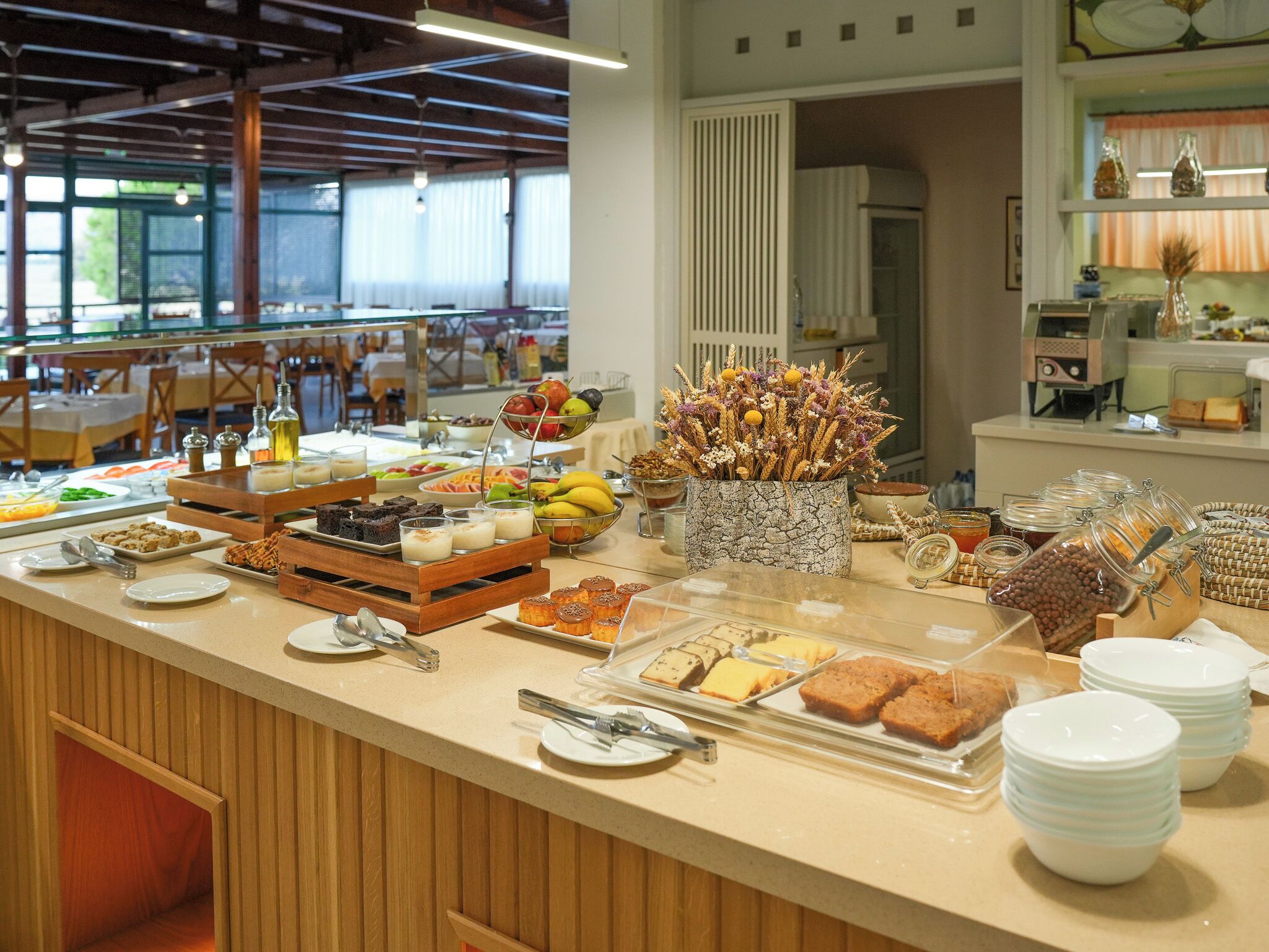 A buffet with various food items and a decorative vase with dried plants.