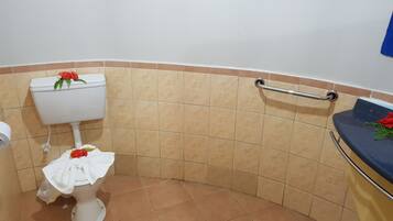 Een badkamer met toilet, een handgreep en een wastafel met handdoek.