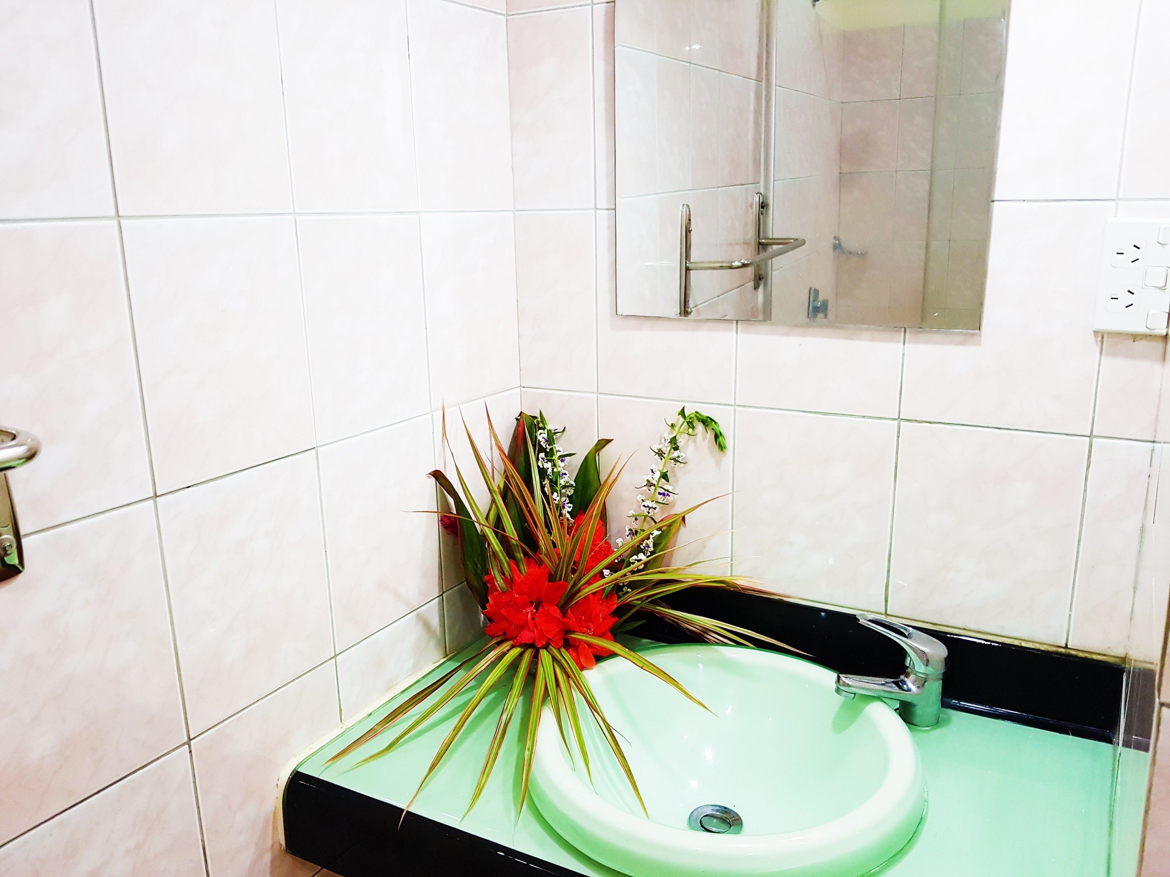 A bathroom with a green sink, white tiled walls, and a mirror above the sink.