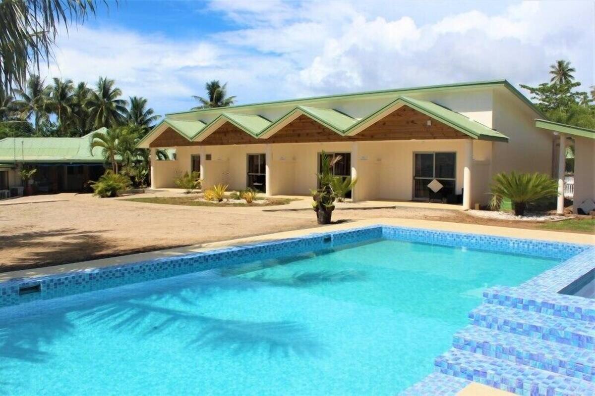 Un hotel con piscina, un área exterior techada y un edificio con techo verde.
