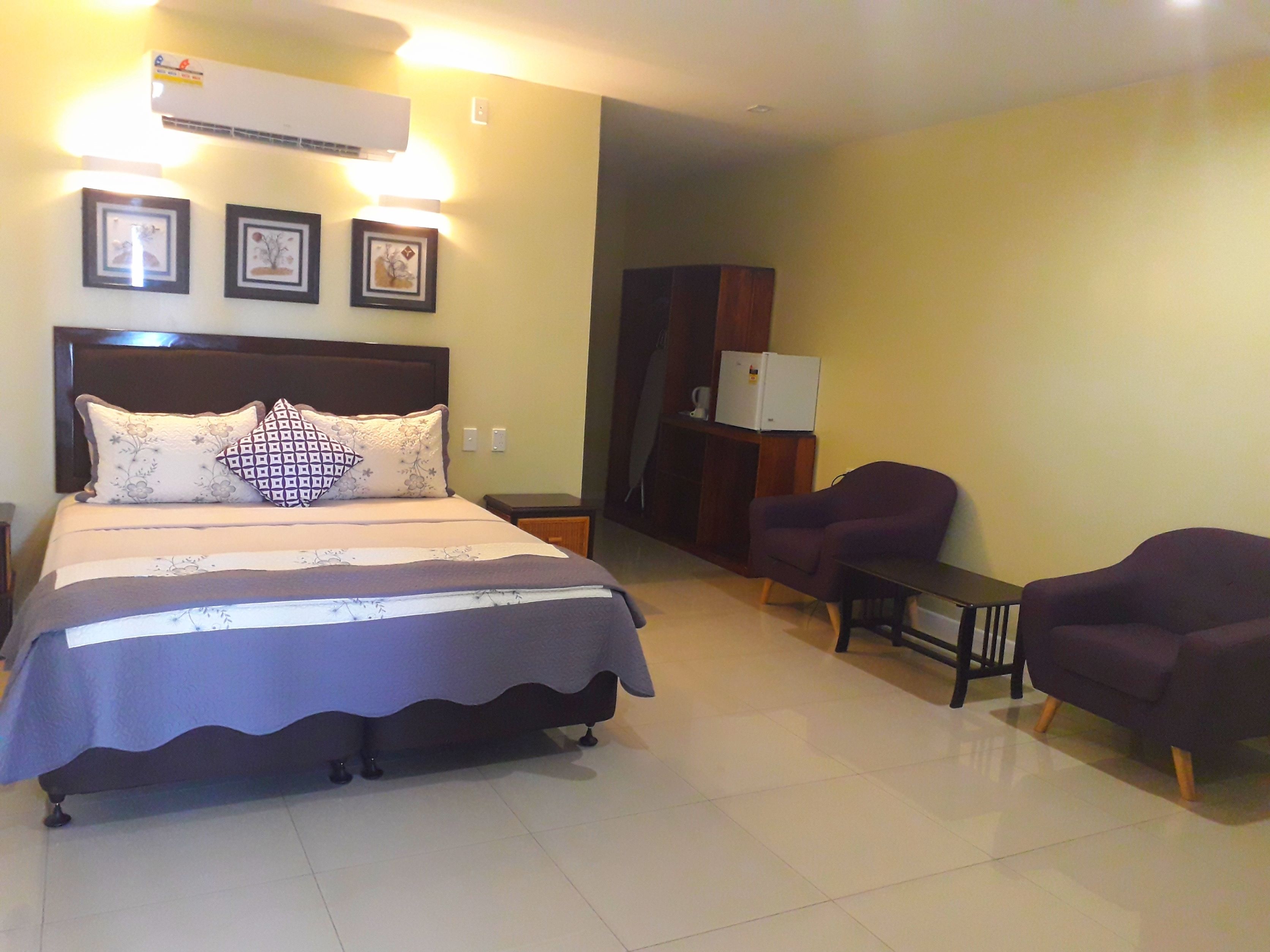 A hotel room with a bed, a desk, a chair, and a wardrobe.
