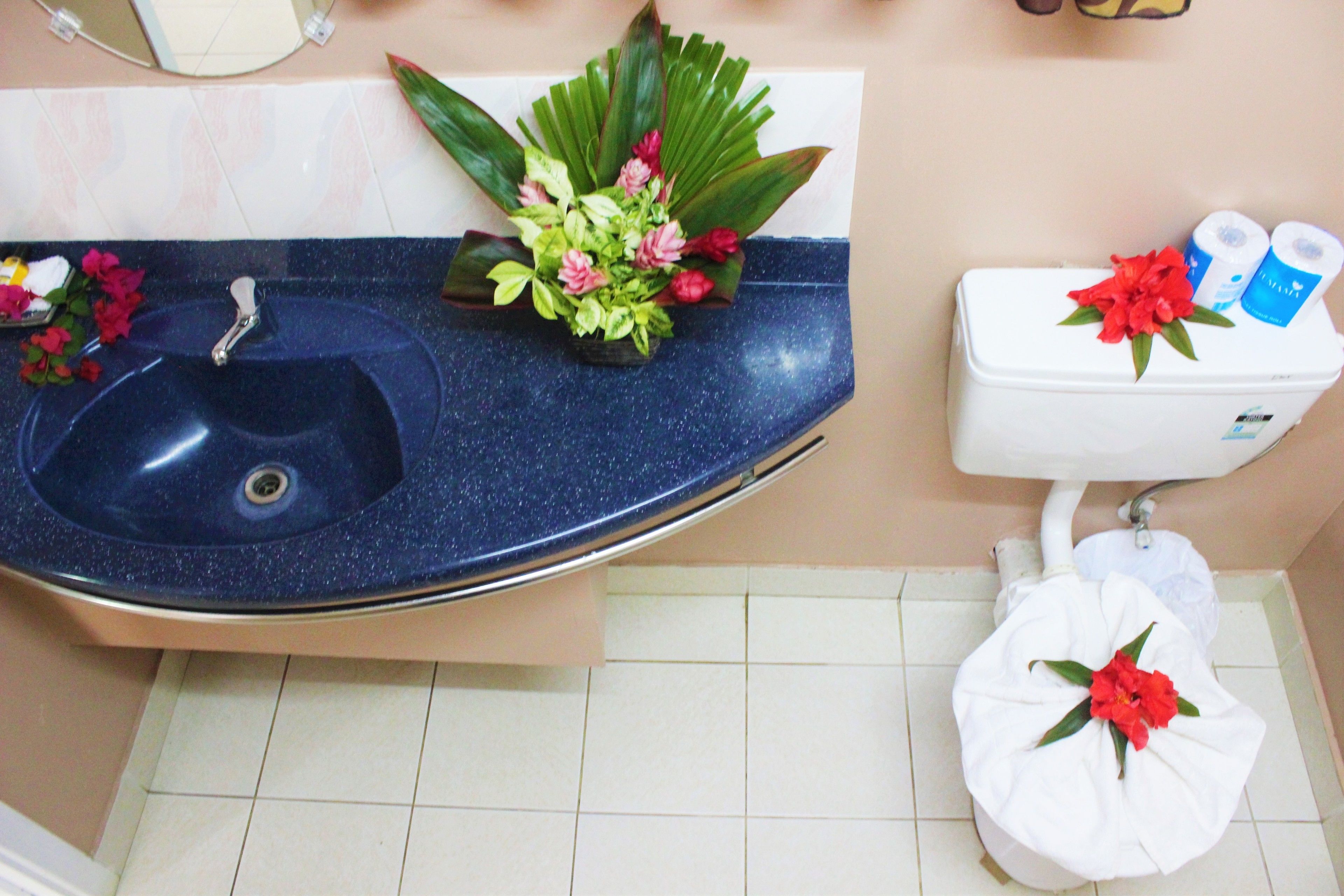 Un baño con un lavabo azul, inodoro y un arreglo de plantas decorativas.