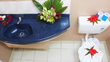 Un baño con un lavabo azul, inodoro y un arreglo de plantas decorativas.
