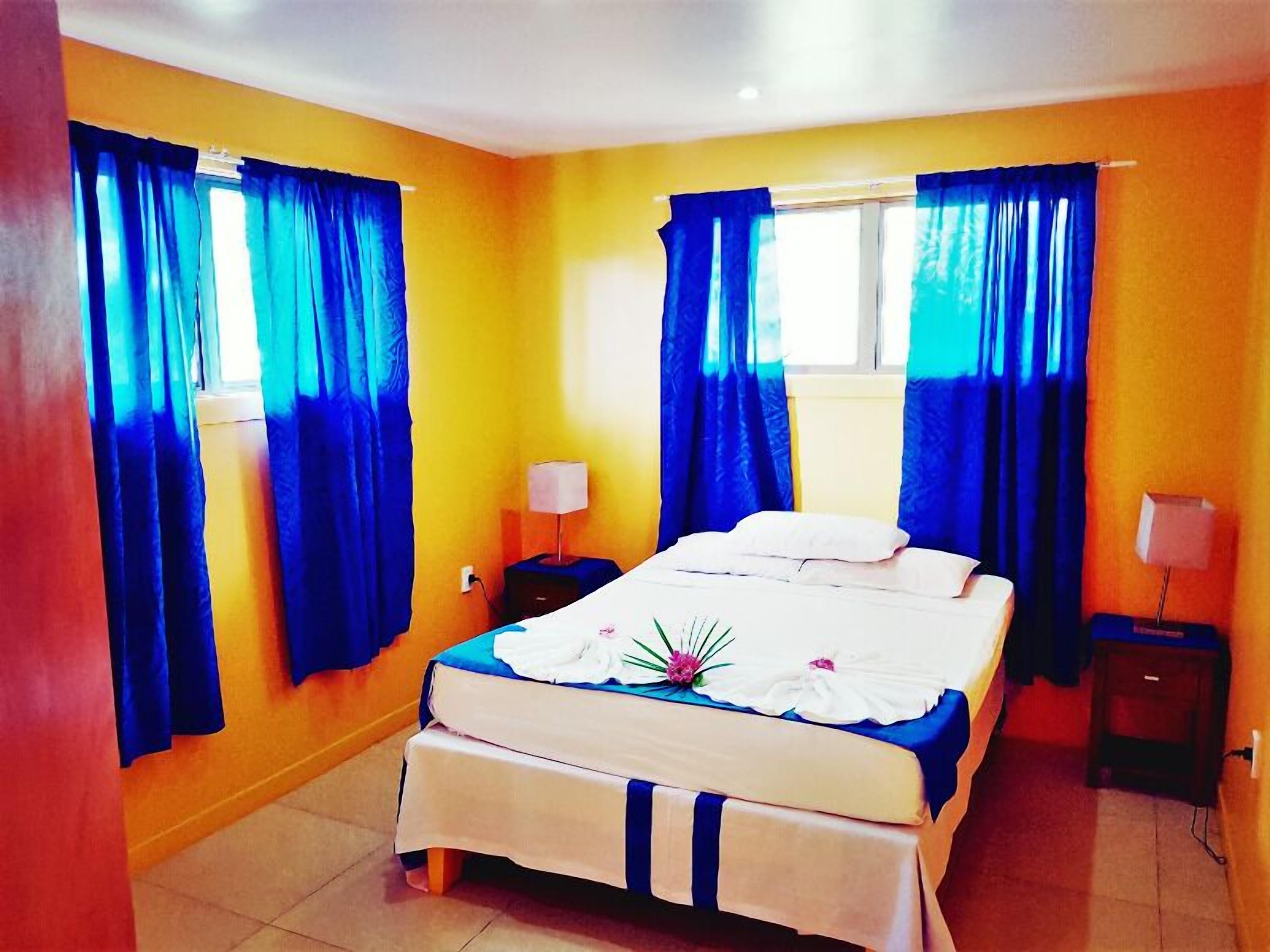 A hotel room with a bed, two bedside tables, and curtains.