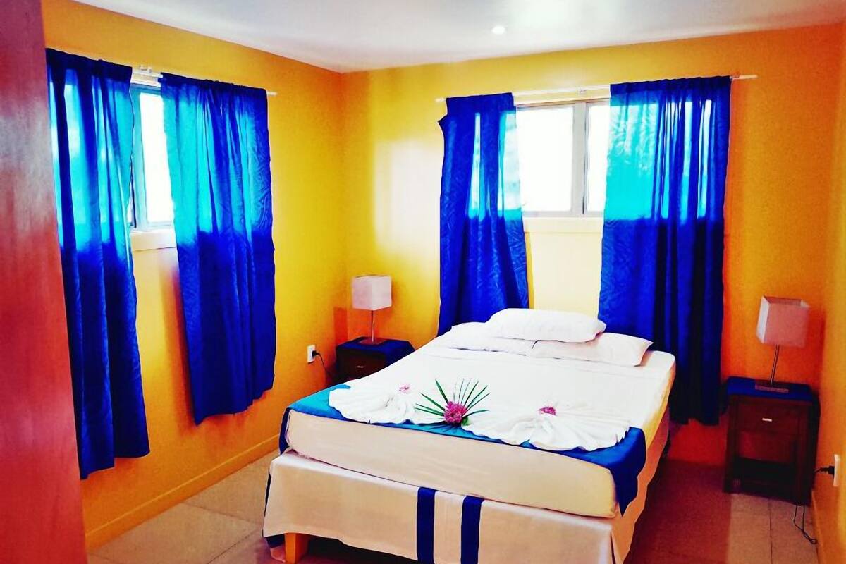 Una habitación de hotel con una cama, dos mesitas de noche y cortinas.