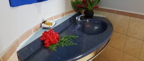 Una cocina con encimera azul moteada, un lavamanos, una planta en maceta y un pequeño recipiente con artículos de aseo.