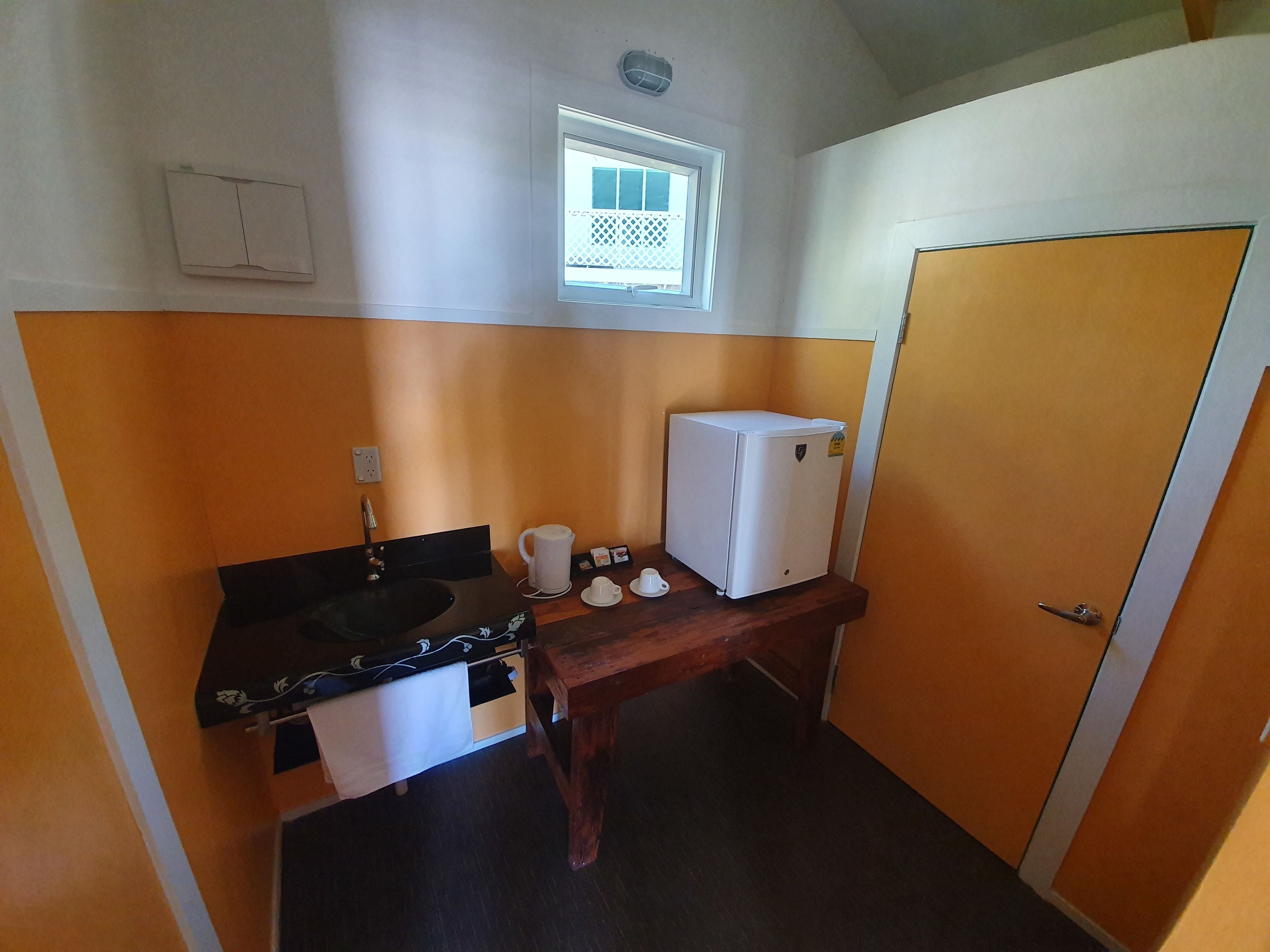 Una cocina compacta con pileta, estufa y un refrigerador pequeño.