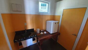 Una cocina compacta con pileta, estufa y un refrigerador pequeño.