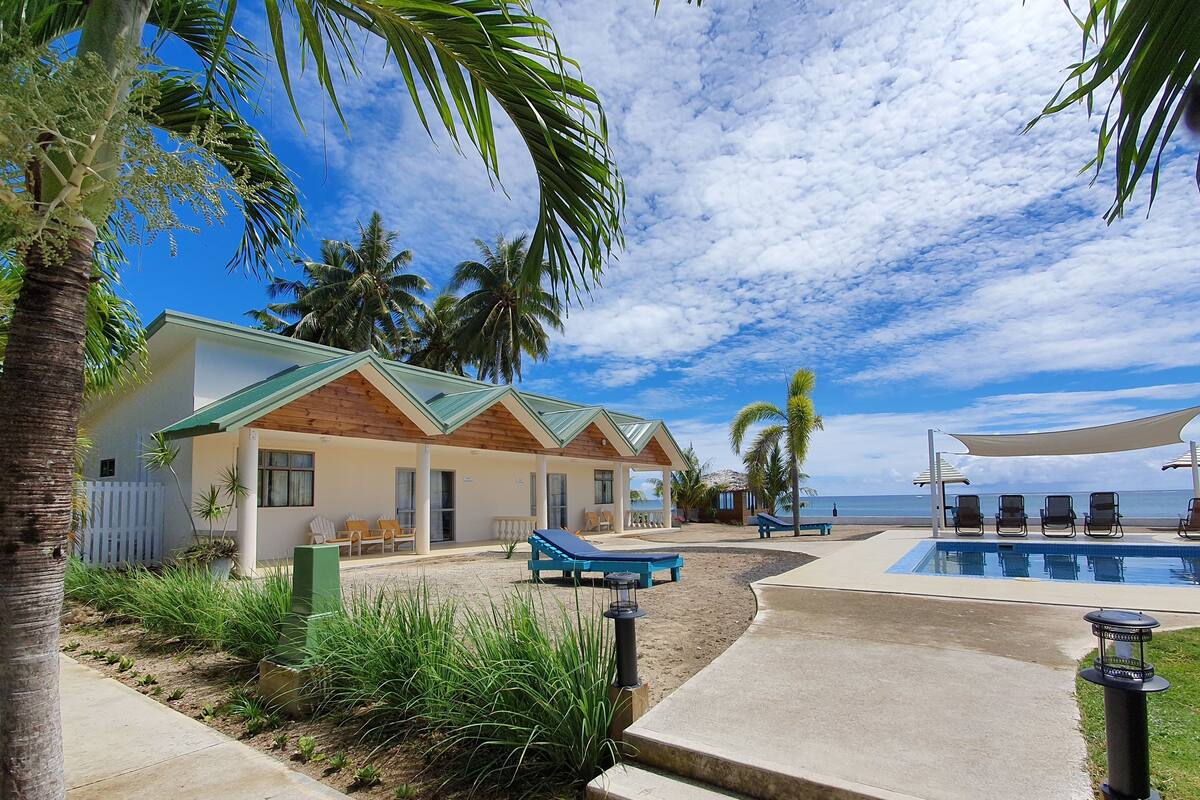 Un resort con piscina, sillones de descanso y palmeras.