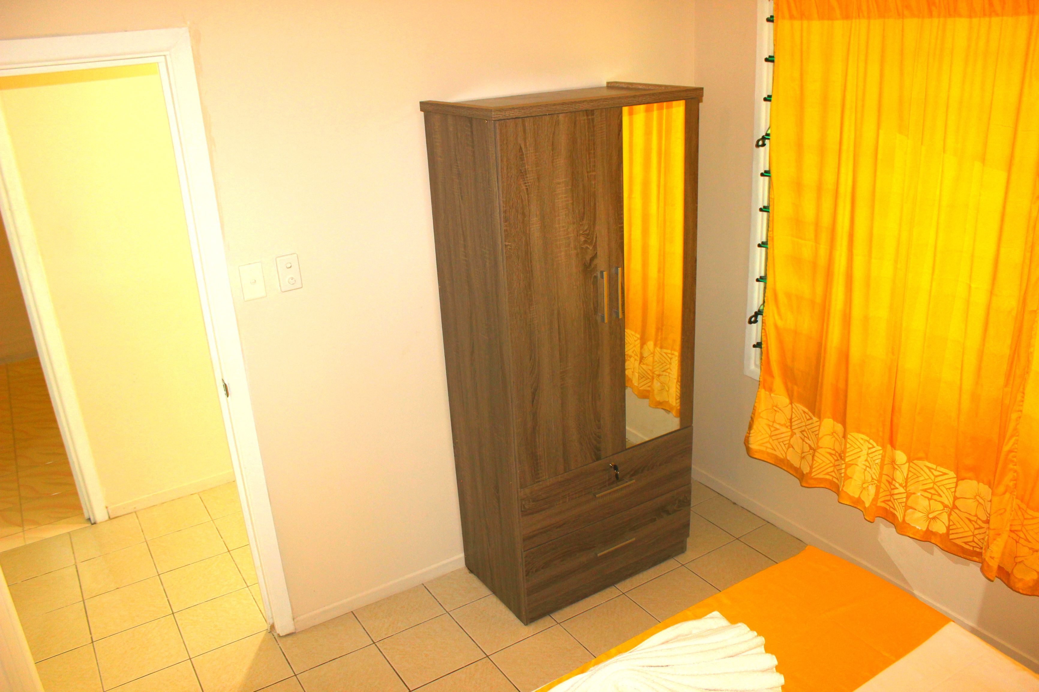 A room with a wardrobe, a bed, and a curtain.