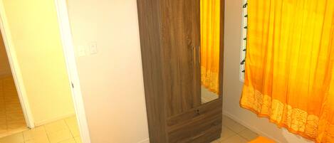 A room with a wardrobe, a bed, and a curtain.