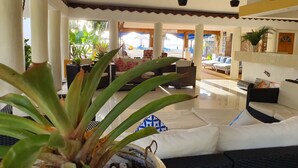 A spacious lobby with a large seating area, a staircase, and a view of the beach. - Le Uaina Beach Resort (Faleapuna)