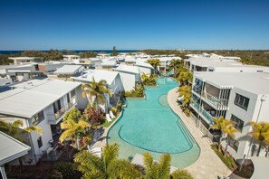 A resort with multiple buildings, a central swimming pool, and a view of the ocean. - Sand Dunes Resort (Marcoola)