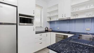 Una cocina moderna con armarios blancos, un refrigerador de acero inoxidable, un microondas y un lavavajillas.