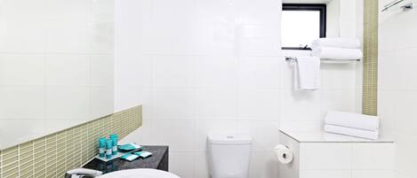 A modern bathroom with a white sink, toilet, and bathtub. There is a small countertop with toiletries and a mirror above the sink.