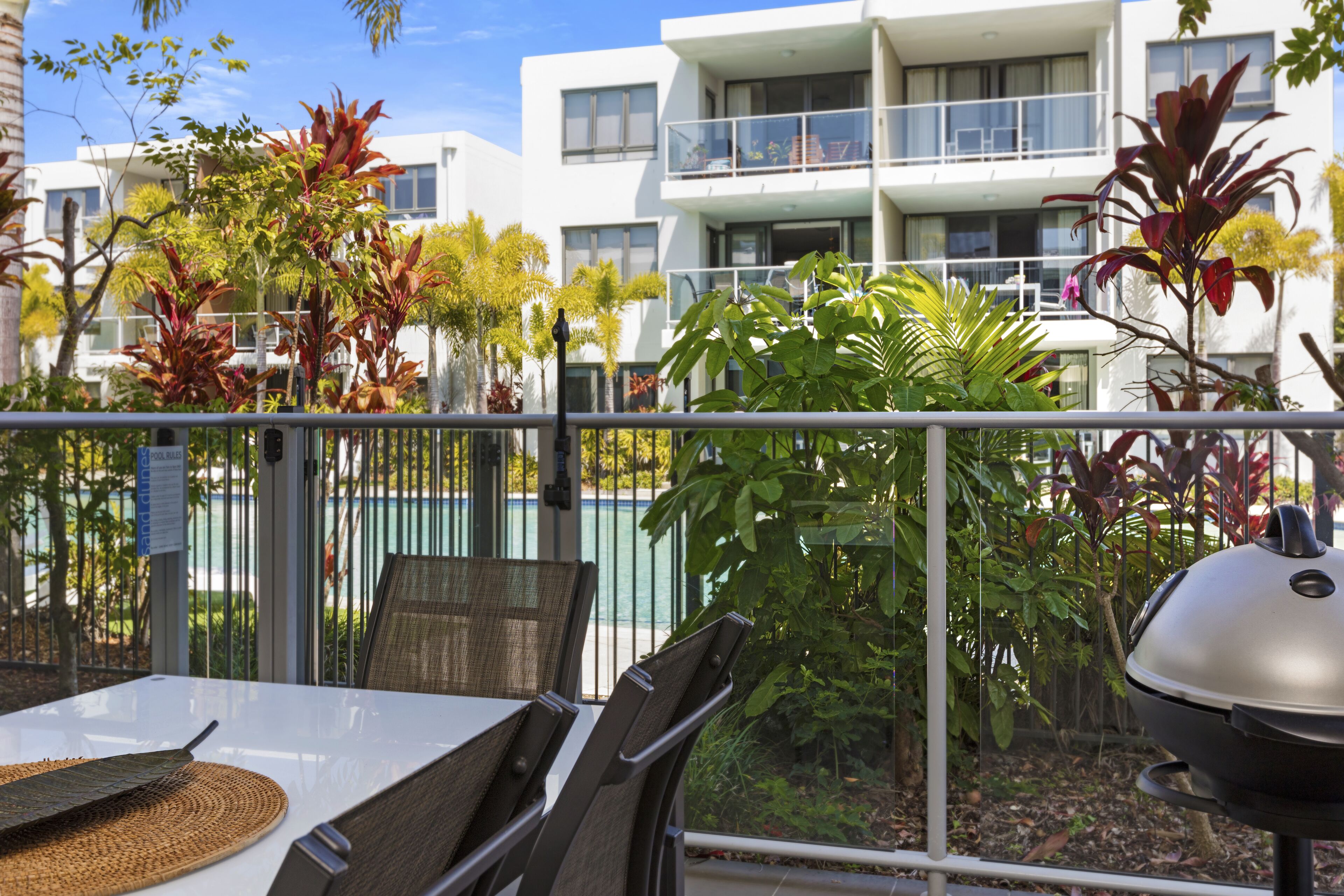 Een balkon met een tafel, stoelen en een barbecue.