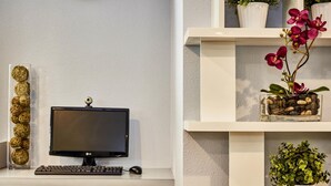 Un escritorio moderno con un monitor de computadora, teclado y ratón. Hay objetos decorativos en la pared y estantes con plantas.