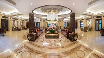 A spacious lobby with a central seating area, a chandelier, and a patterned floor.