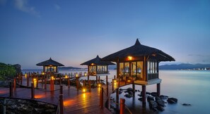 A wooden deck with thatched-roof structures, overlooking calm water. - Vinpearl Luxury Nha Trang (Nha Trang)
