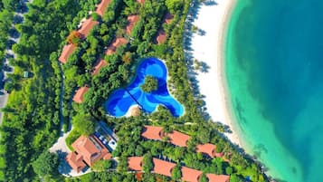 Relax in a villa with its own pool, surrounded by lush greenery and beach access.