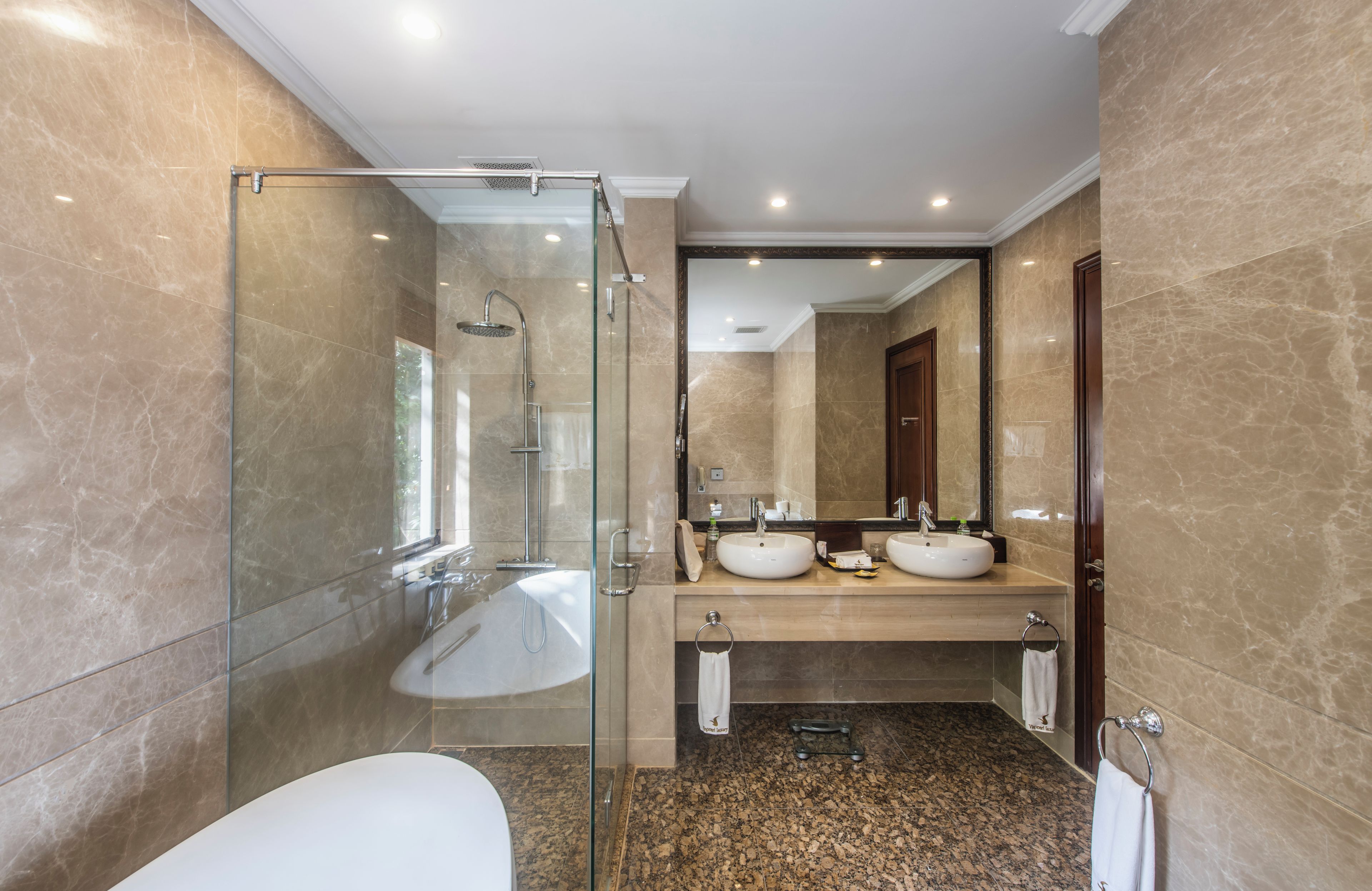 A modern bathroom with a glass-enclosed shower, two sinks, and a large mirror.