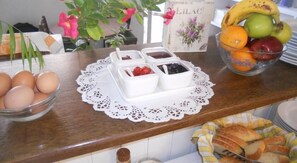 A breakfast buffet with various food items including eggs, jams, and fruits.